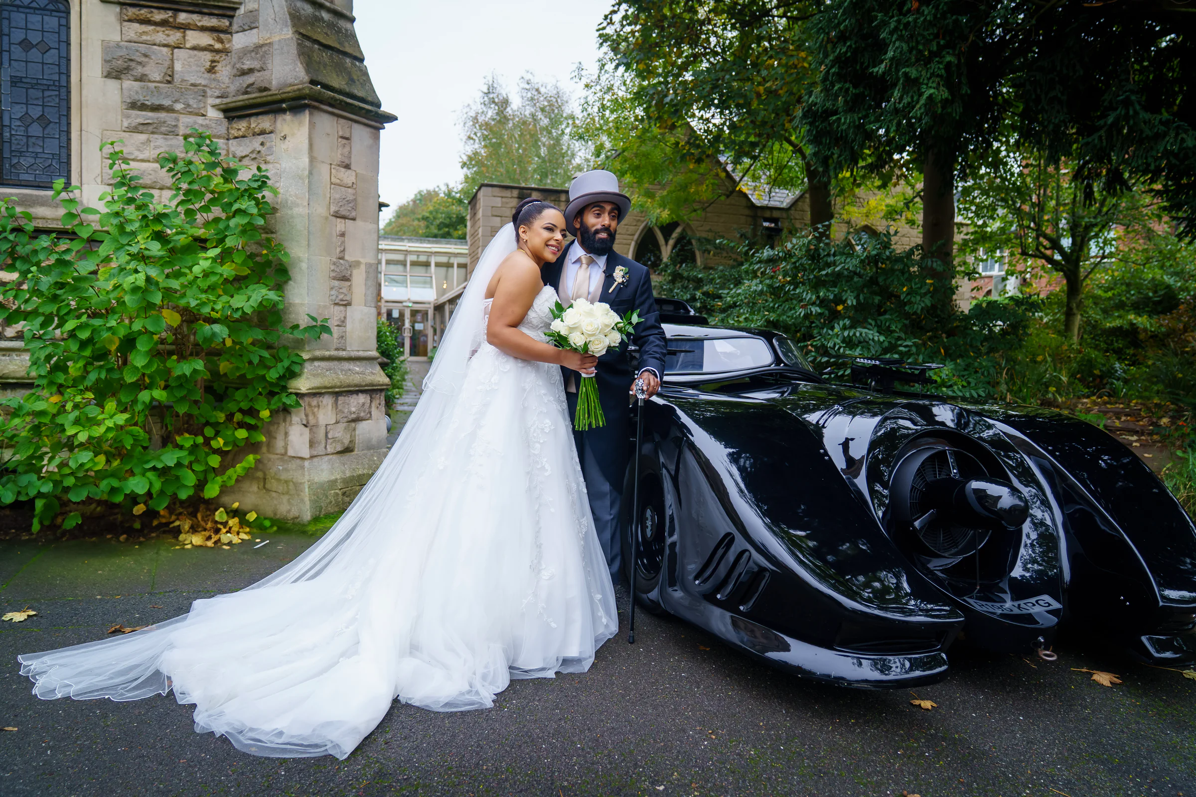 Newlyweds standing beside a classic car