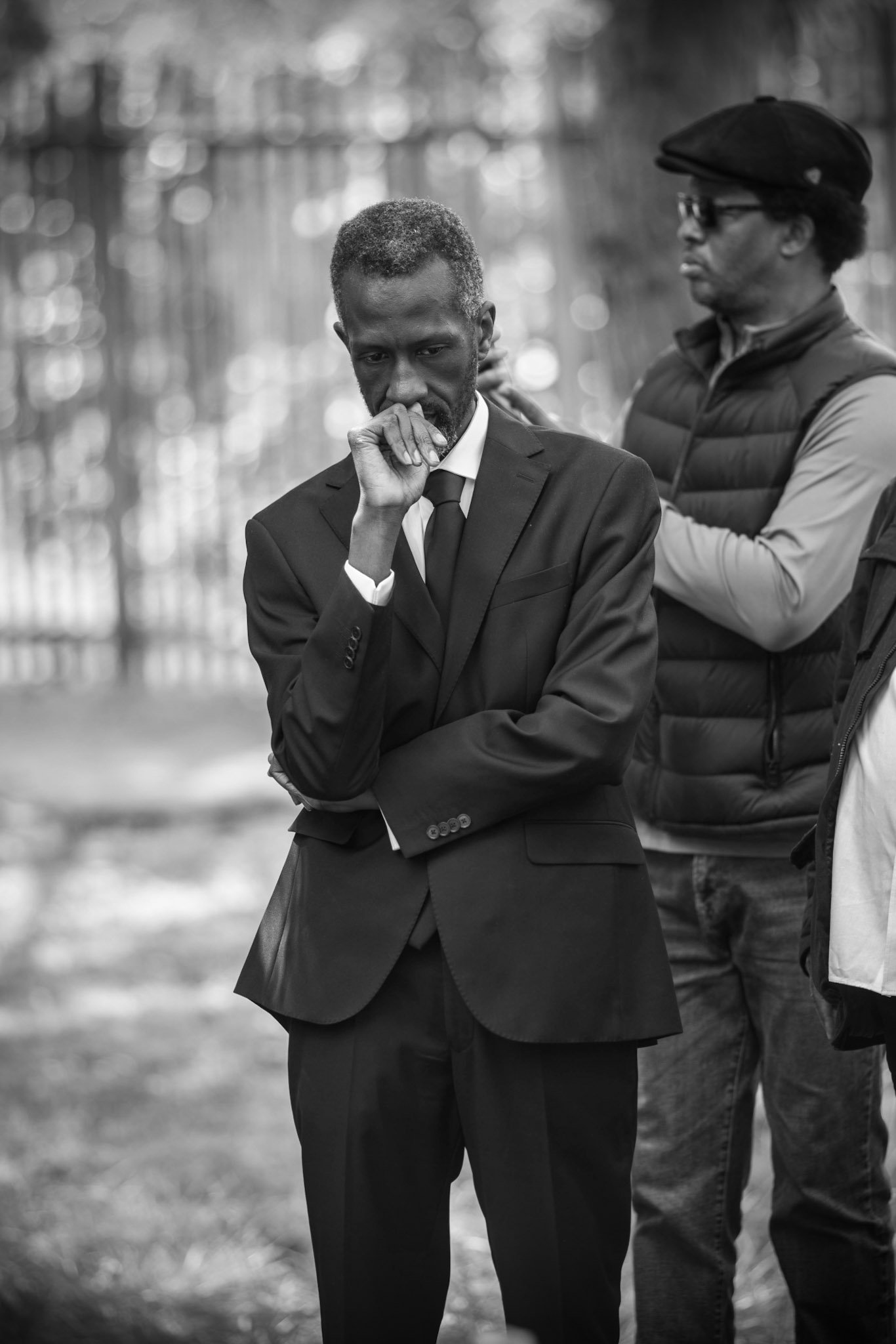 Man in a suit standing beside another man outdoors