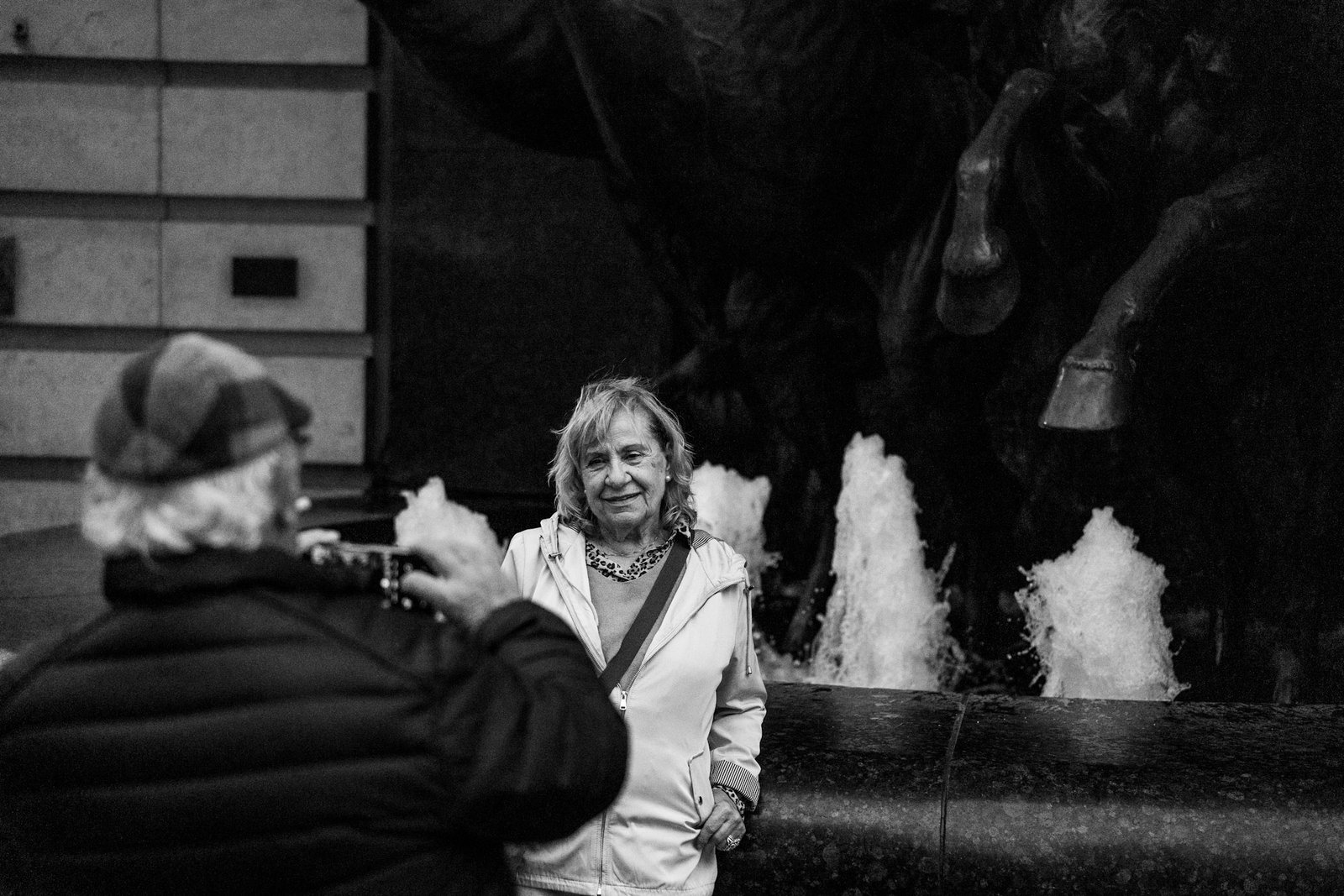 Woman smiling beside a fountain as someone takes her photograph