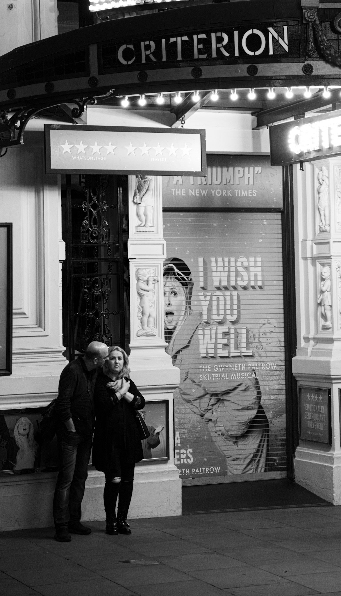 Two people standing outside the Criterion Theatre