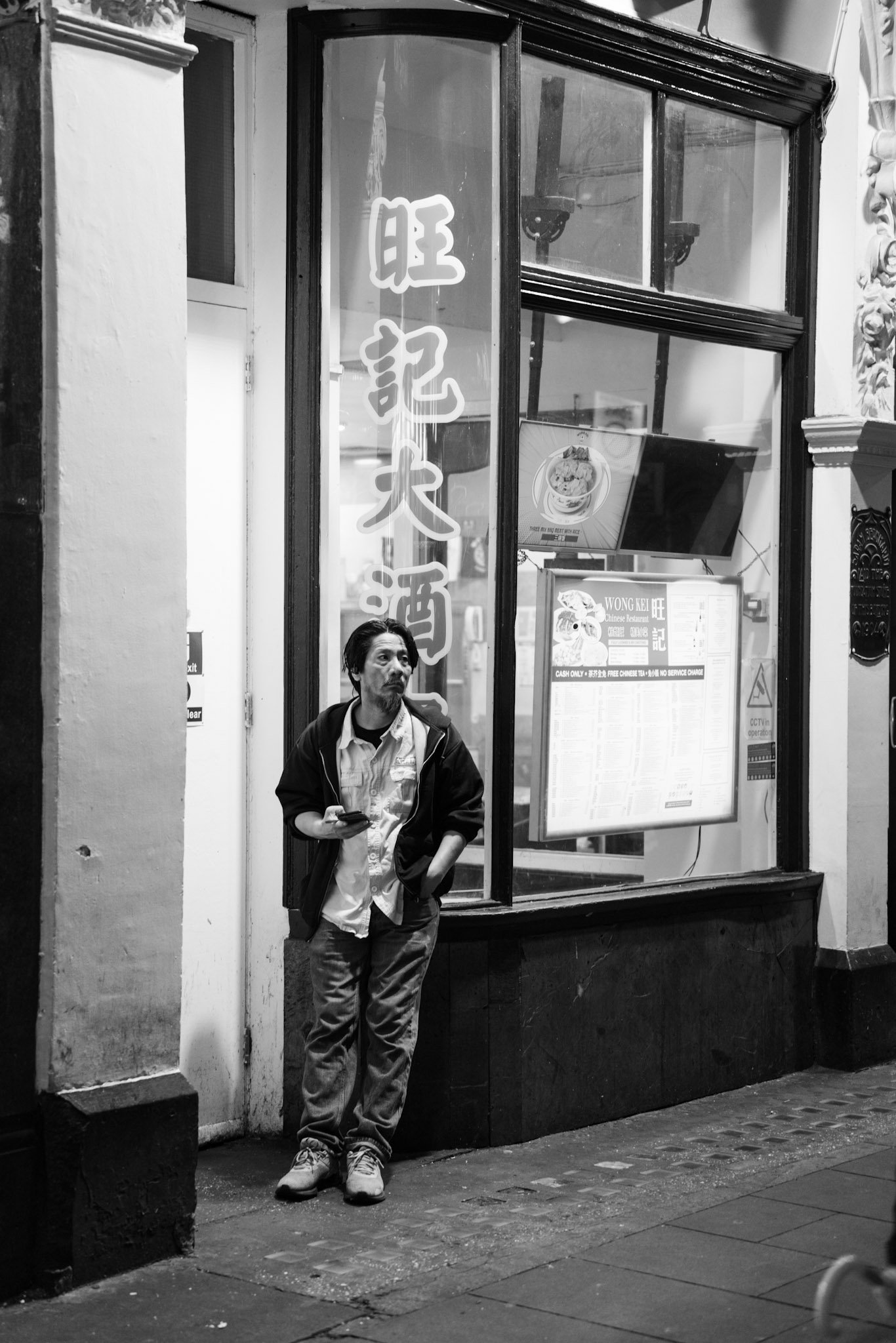 Man leaning beside a city shopfront