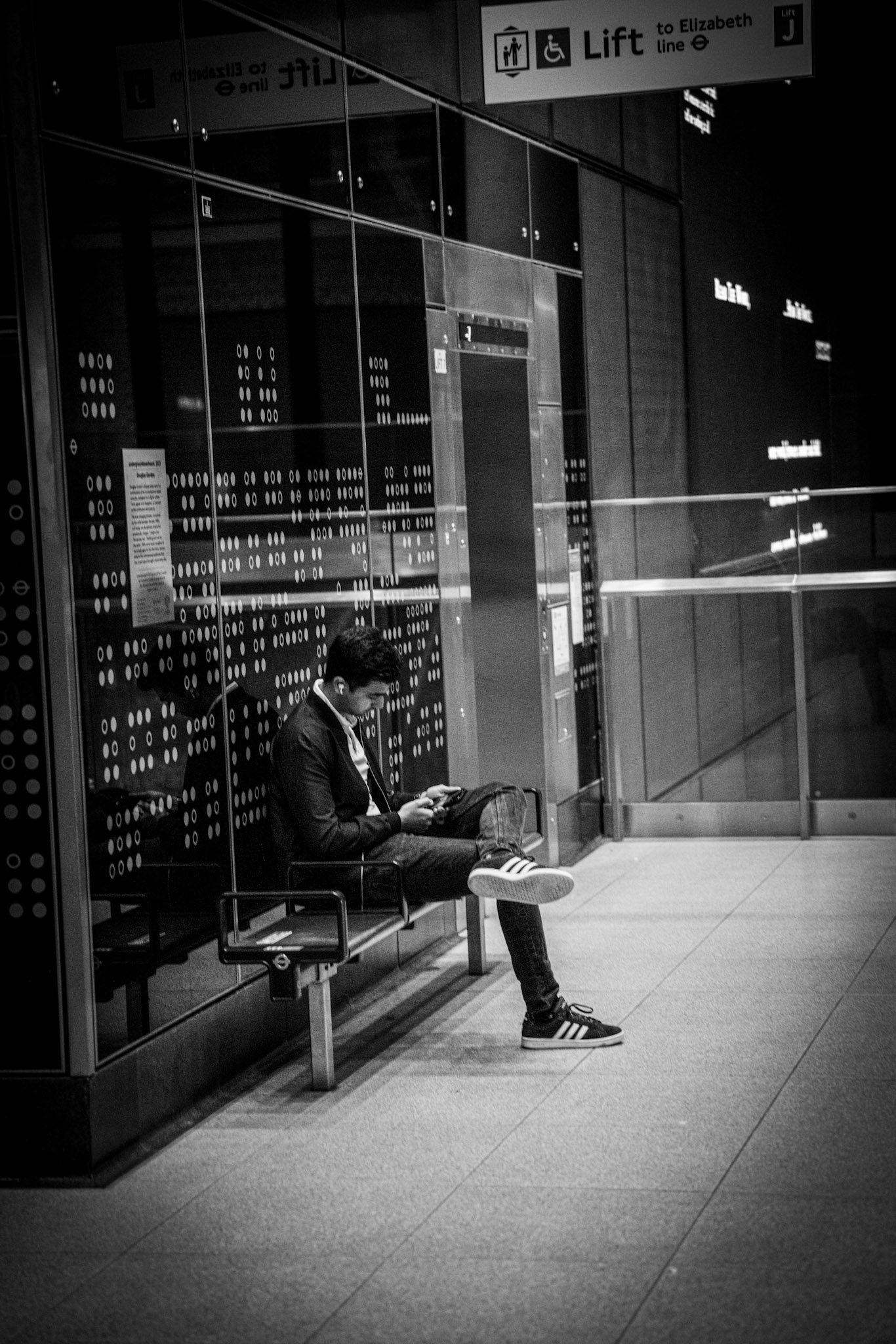 Person seated outside a city shop at night