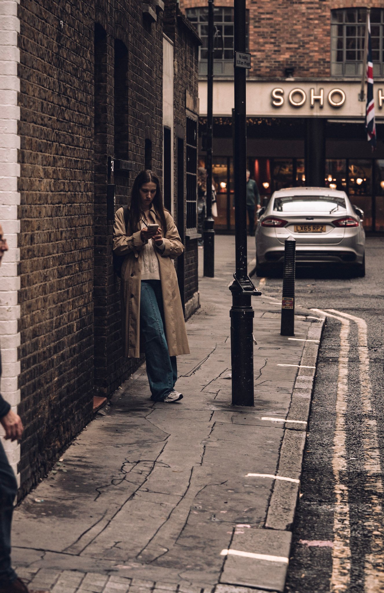 Woman leaning against a brick wall in Soho
