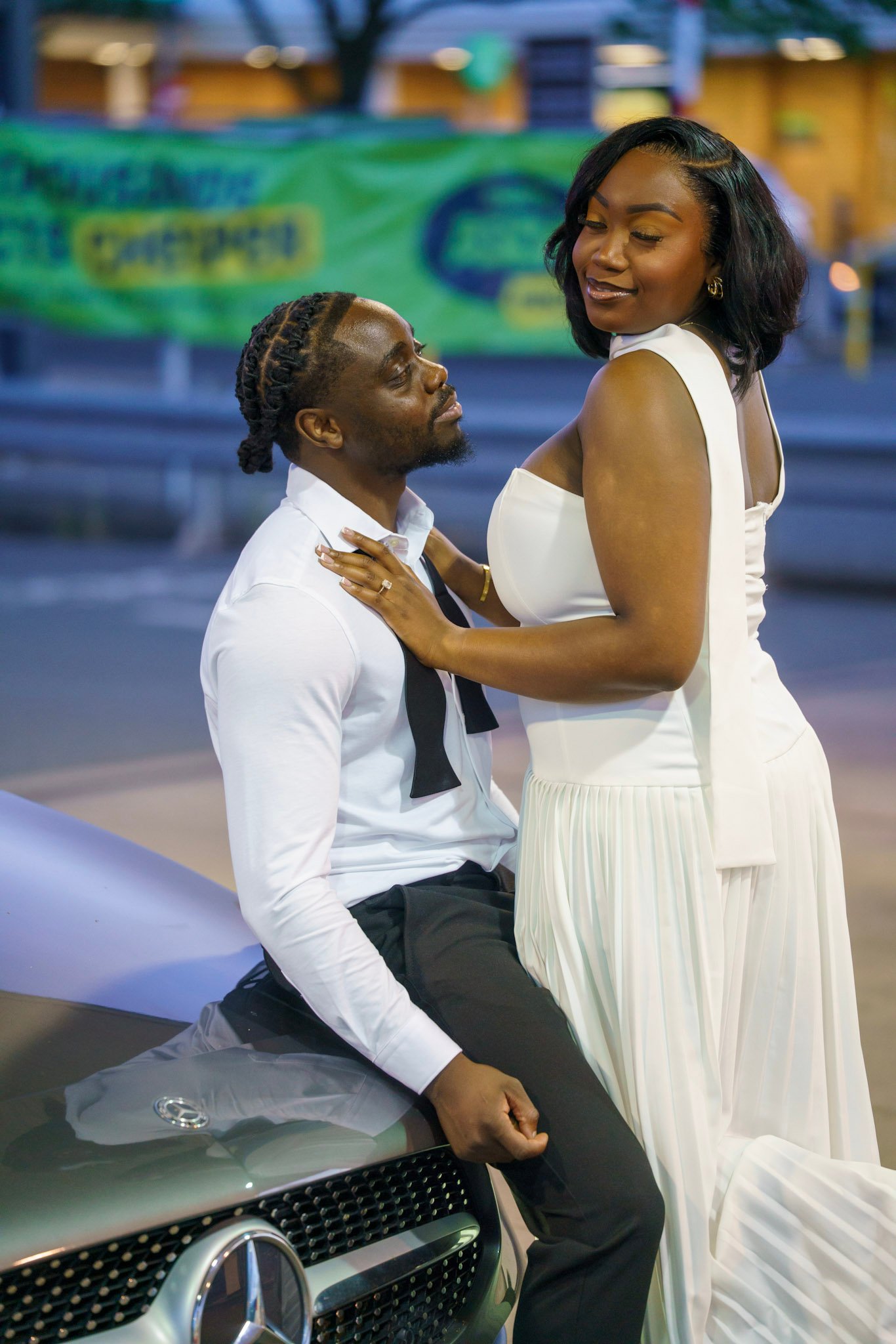 Bride and groom posing together beside a car