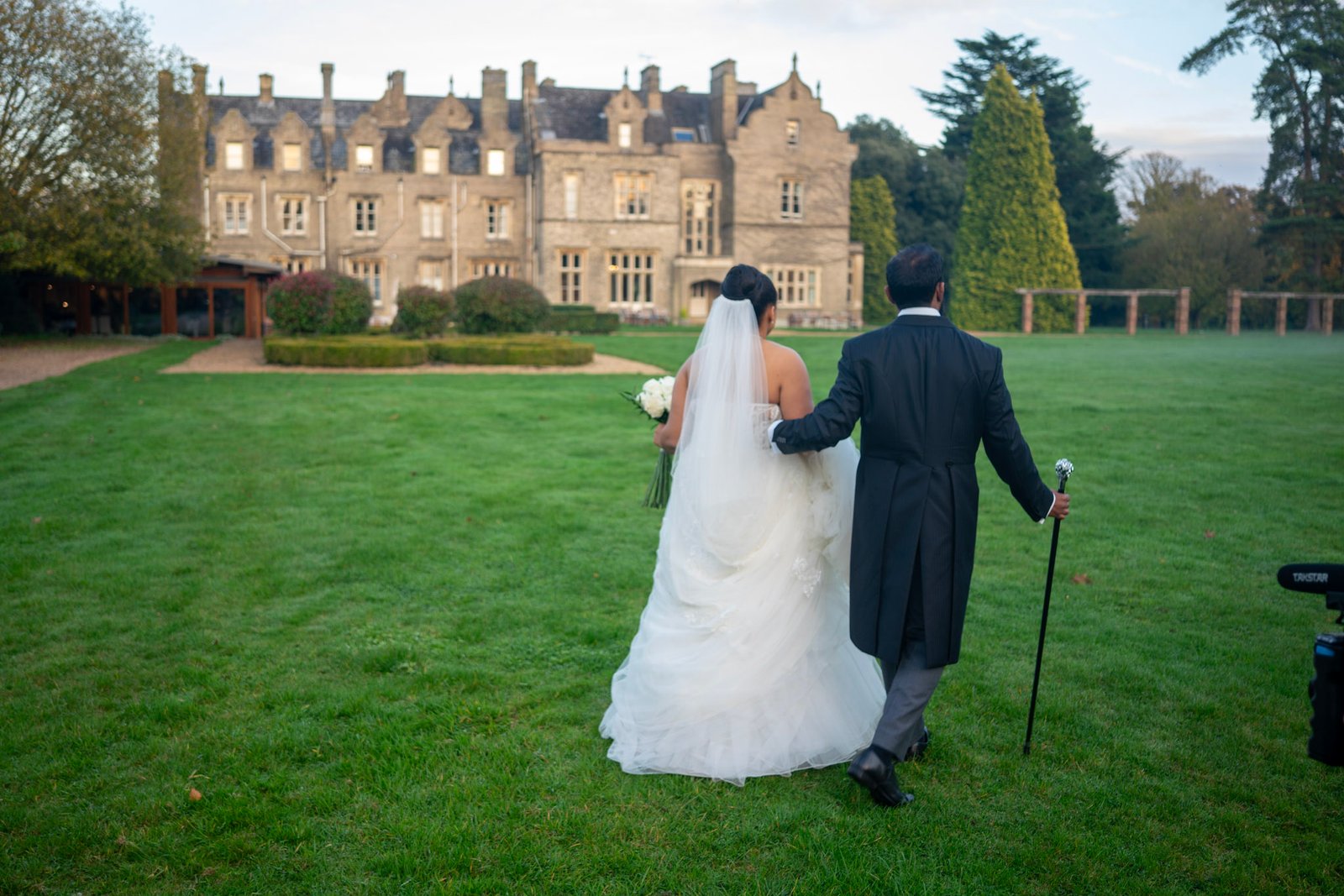 Bride and groom walking across a lawn